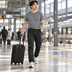 Phantom card travel — Adult traveler walking through a station wearing Phantom IX9 black pants beside a suitcase.