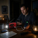 Hombre cargando un teléfono desde la radio de emergencia durante un corte de energía a la luz de las velas