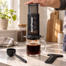 Mano presionando el émbolo de AeroPress para preparar café en una taza de vidrio