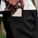 Mano guardando un teléfono en el bolsillo lateral de unos chinos negros