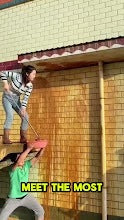 Hombre usando una manguera de jardín al aire libre junto a una pared de ladrillo