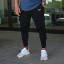 Hombre vestido con joggers Performance Tech negros con zapatillas blancas