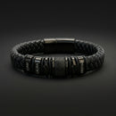 Pulsera negra grabada dispuesta en círculo sobre una superficie oscura