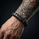 Pulsera negra personalizada en una muñeca tatuada