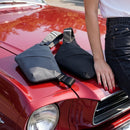 Persona junto a un auto con bolsos cruzados compactos exhibidos sobre el cofre