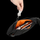 Bolso Slim Carry 3 abierto con forro naranja y objetos esenciales guardados