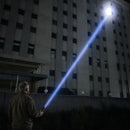 Hombre apuntando con un haz de linterna IRONCLAD hacia un edificio alto por la noche