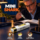 Linterna Mini Shark blanca y dorada con lente frontal y panel lateral, junto a una persona leyendo.