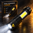 Linterna negra Mini Titanium Laser con luces frontales y laterales iluminadas junto a su caja en una escena de estudio oscura