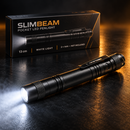 Linterna tipo lápiz negra SlimBeam con luz blanca iluminada y clip de bolsillo visible junto a su caja en una escena de estudio oscura